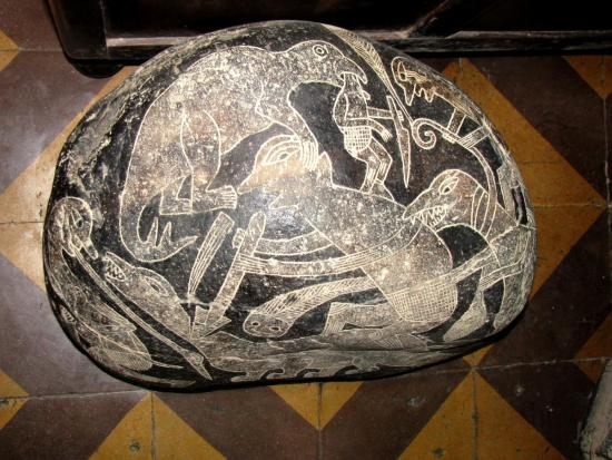 Камень с изображением битвы людей с динозаврами.